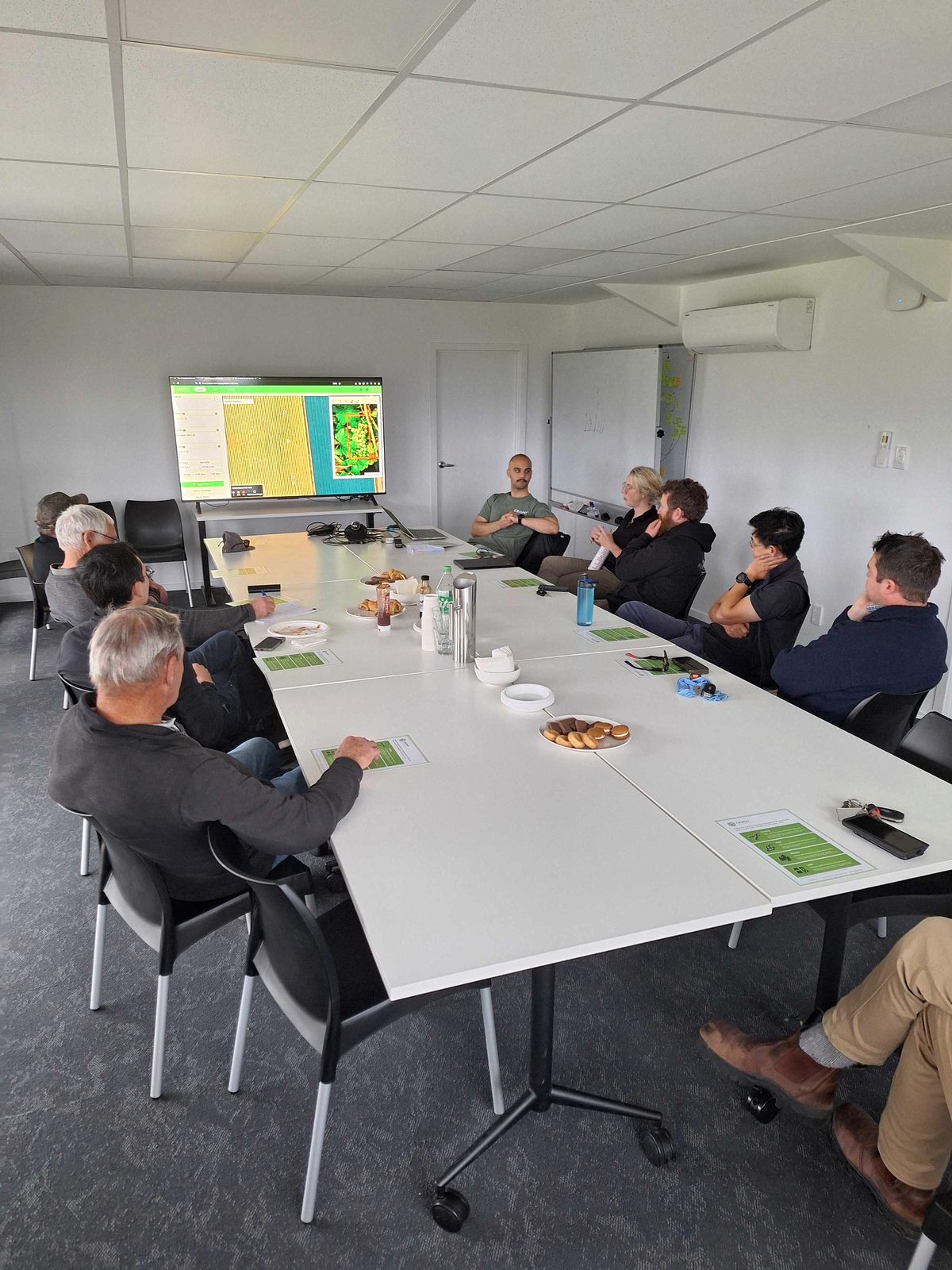 Growers and Cropsy staff around a long boardroom table, vineyard maps on the wall screens