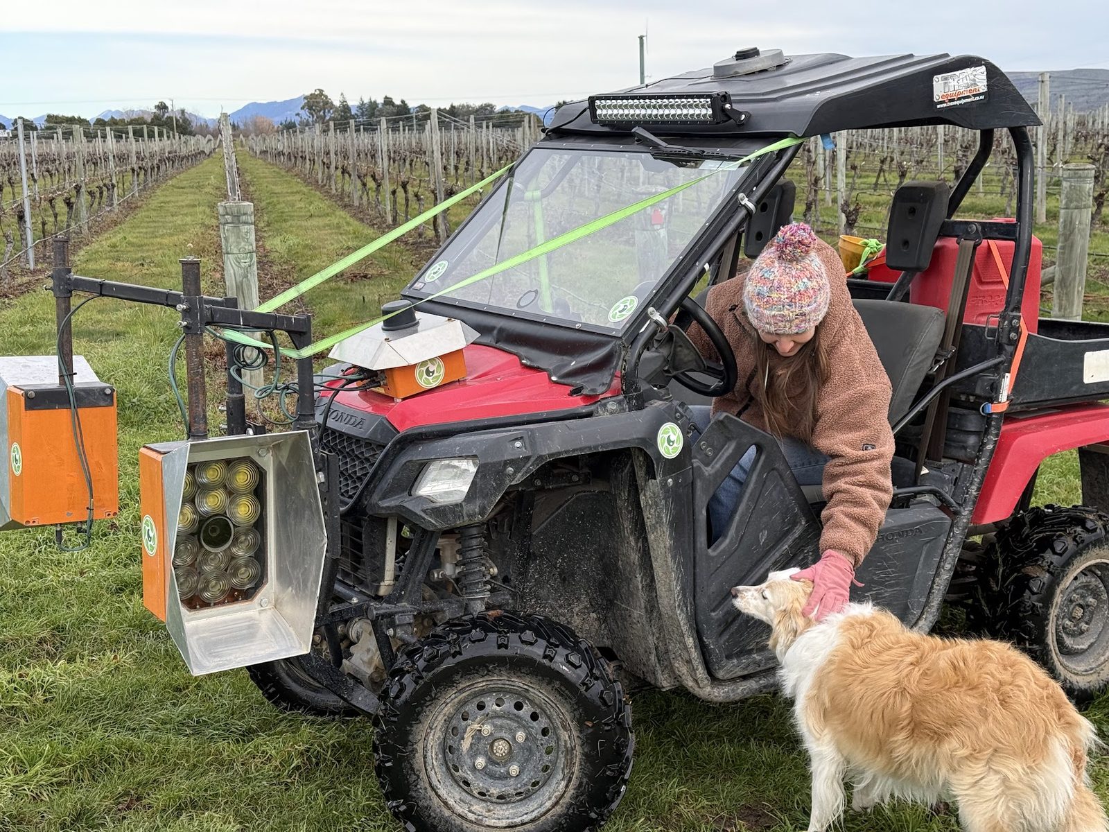 A grower leaning on a red Honda buggy fitted with Cropsy scanner units, a farm dog beside the wheel