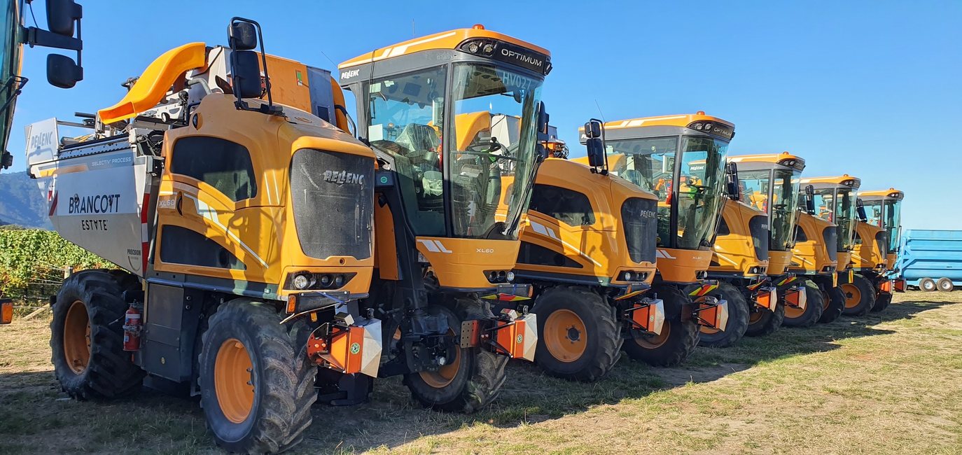 A line of yellow Pellenc Optimum XL60 grape harvesters, each fitted with orange Cropsy scanner units